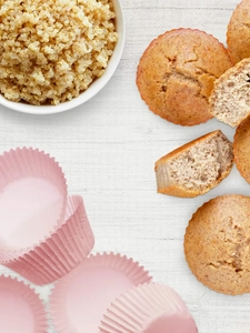 A view from above of a bowl of cooked quinoa and fluffy muffins. 