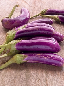 Purple aubergines on a wooden counter.