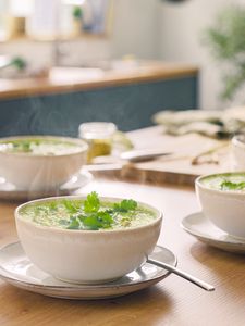 Suppe in Keramikschalen auf Küchenplatte mit Garnitur.