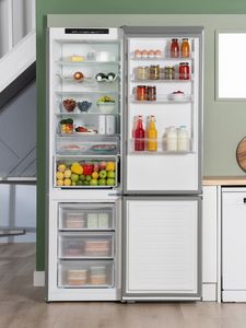 Bosch fridge freezer with the door open, displaying various food items and beverages inside.             