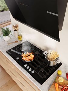 Une cuisine moderne avec une plaque gaz noire, crevettes sautées et pâtes en ébullition.