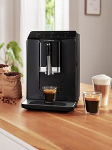 Hot mug of black coffee next to coffee machine on countertop