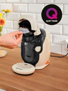 Person putting pod in Tassimo machine, with Quiet Mark icon
