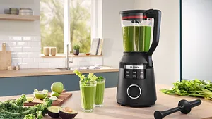 Batidora de alto rendimiento VitaBoost Series 6 de Bosch con frutas y verduras y un vaso para batidos en un estante de la cocina.