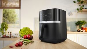Uma Air Fryer Serie 4 da Bosch está numa bancada de cozinha moderna, vista de frente, pronta para cozinhar.