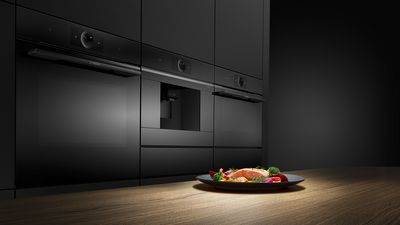
       Serie 8 accent line ovnserie i et køkken. På bordet er der en tallerken med tilberedt laks og grøntsager.
      