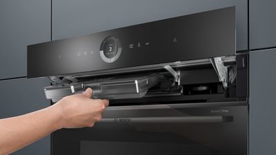 
       Serie 8 accent line ovn. En person trækker vandtanken ud, som er placeret bag det åbne betjeningspanel.
      