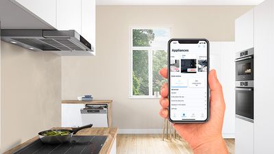 Smartphone with open Remote Diagnostics app is held in the hand in a kitchen.