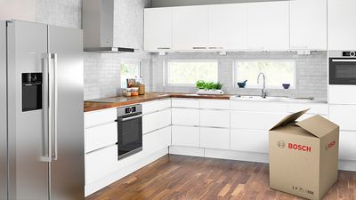 Bela kuhinja sa drvenom radnom površinom, pločom za kuvanje i mašinom za pranje sudova.