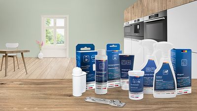 Different cleaning and care products on a white kitchen countertop.