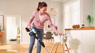 Жена, която използва Bosch Unlimited 7 ProHygienic Aqua, за да измие и почисти пода в една стъпка. Тя лесно маневрира с уреда около детското столче в кухнята.