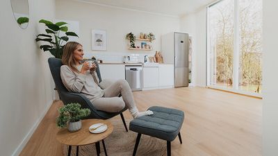 Diferentes productos de limpieza y mantenimiento Bosch y documentos sobre una mesa blanca en una cocina abierta.