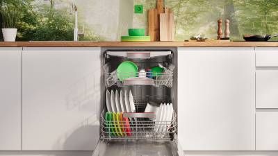 Lavastoviglie in acciaio inox con porta aperta, piano in legno e pareti bianche in cucina moderna.