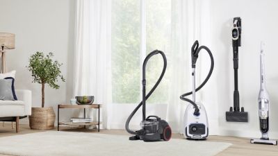 Soggiorno moderno con diversi aspirapolvere Bosch, a traino e senza filo, disposti in fila