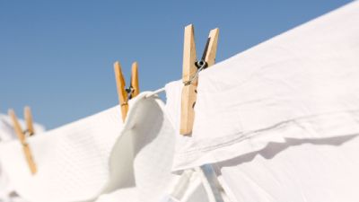La biancheria bianca tenuta da mollette di legno su uno stendibiancheria contro un cielo azzurro e limpido.