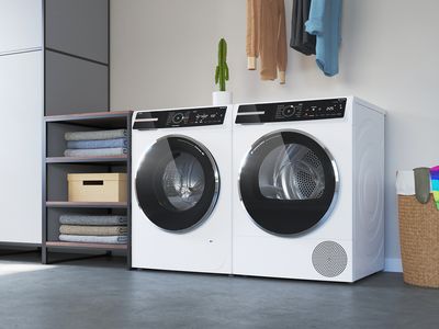 Freistehende Bosch Waschmaschine mit Trockner in einem modernen weißen Waschraum.