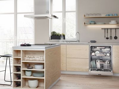 Baltos ir medienos apdailos virtuvė su atidarytu pirkrautu prietaisu.