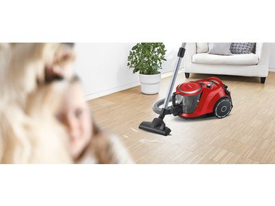 Two Bosch bagless cylinder vacuums stand on a cream rug in a light, bright living room.