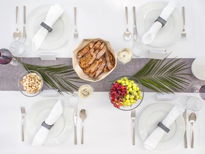 Draufsicht auf einen Tisch, der für das Abendessen eingedeckt und mit Blumen und Palmblättern dekoriert ist.