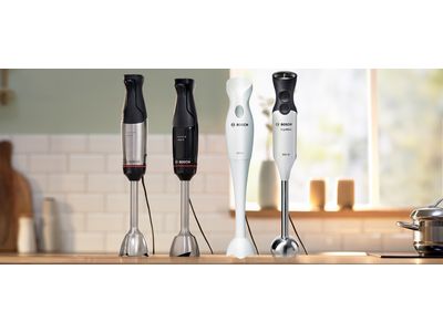 Bosch hand blender standing on a wooden counter in a bright, airy kitchen.