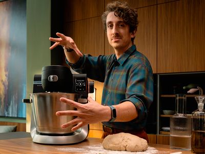 Osoba u kuchyňské linky s mixérem nad hromadou těsta nadšeně gestikuluje.