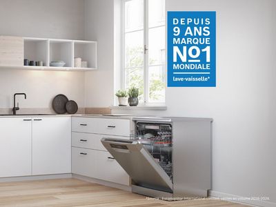 Un lave-vaisselle pose-libre ouvert dans une cuisine blanche et lumineuse.