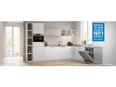 Un lave-vaisselle pose-libre ouvert dans une cuisine blanche et lumineuse.