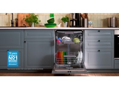 A modern kitchen featuring a Bosch dishwasher with colorful dishes inside.