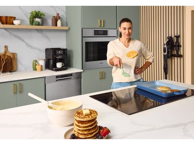 Un &icirc;lot avec une table de cuisson &agrave; induction dans une cuisine blanche en bois.  