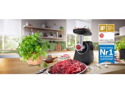 MultiPower Serie 4 z przystawką do mielenia mięsa oraz talerz ze zmielonym mięsem obok talerza z kiełbasą na blacie kuchennym.