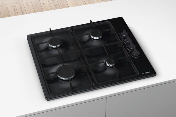 A Bosch Series 2, 4-burner hob in black enamel that's in the centre of a slim white island.