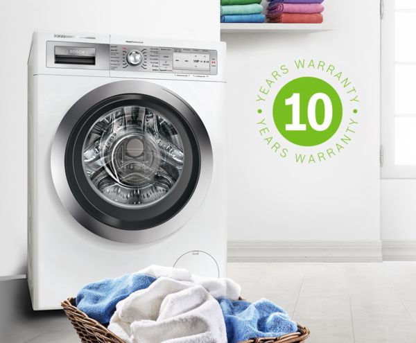 Bosch vrijstaande wasmachine met een berg wasgoed op de vloer. Het groene garantiepictogram van 10 jaar staat voor de verlengde waarborg op de motor.
