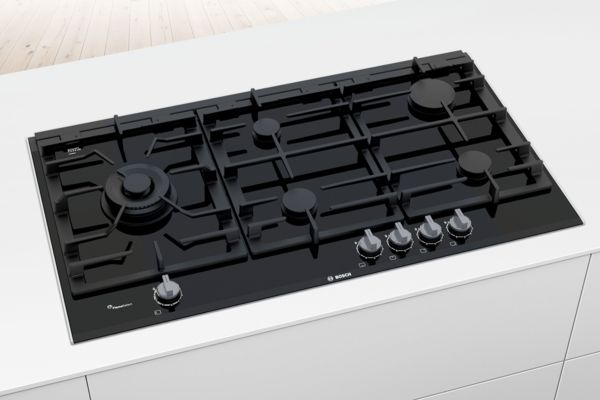 A black tempered glass gas hob from the Bosch Series 6 range built in to a sleek white island.