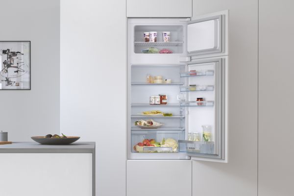 Ein 60 cm breiter Einbau-Kühlschrank von Bosch mit geöffneter Tür zeigt Lebensmittel und Getränke im Innenraum.