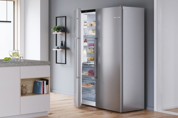 Cuisine moderne avec un réfrigérateur familial side-by-side Bosch. Porte faisant entrevoir des provisions.