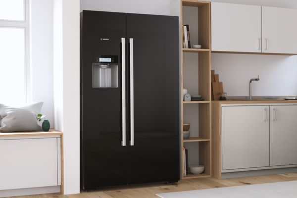 Schwarzer freistehender Kühlschrank von Bosch mit zwei breiten Türen in einer hellen, modernen Küche.