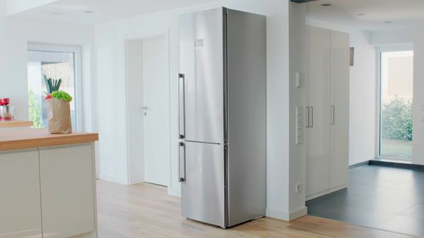 Extra large Bosch fridge-freezer standing at the wall in a kitchen with grocery shopping bag on the kitchen island.  
