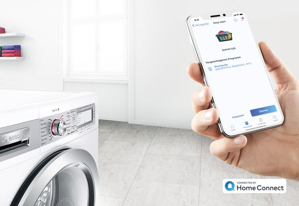 Smartphone mit geöffneter Home Connect App vor einer Waschmaschine von Bosch.