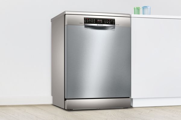 Frittstående Bosch oppvaskmaskin i rustfritt stål på et hvitt kjøkken