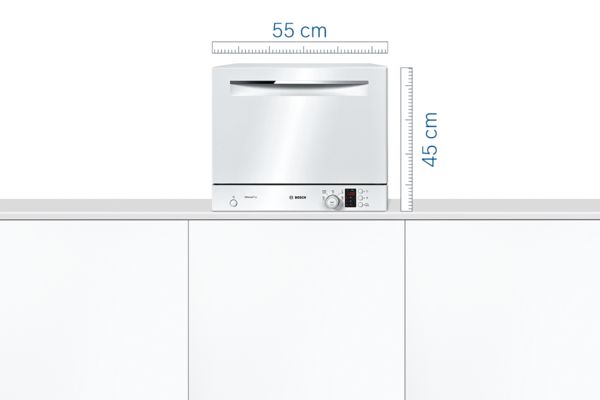 Mini lave-vaisselle Bosch blanc sur un plan de travail dans une cuisine blanche.
