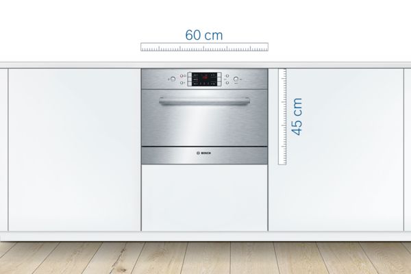 Built-in, compact 60 cm wide Bosch dishwasher in stainless steel integrated into a white kitchen.
