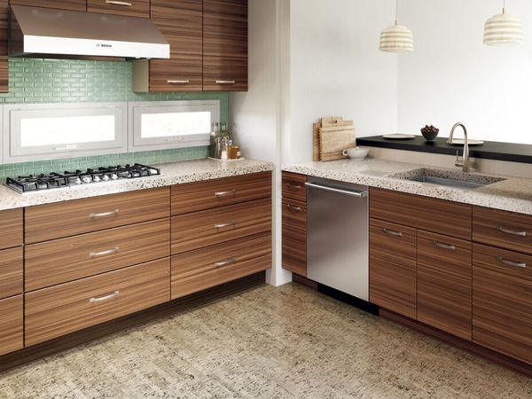 Small L-shaped kitchen in a 1970s style with striated wood cabinets, a gas hob and hood, and built-in stainless-steel dishwasher.