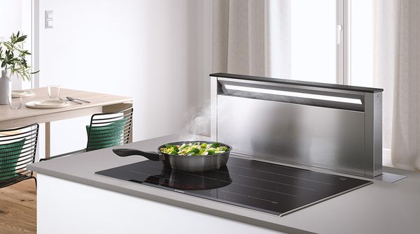 Plein de place pour préparer à manger : une grande table à induction avec hotte intégrée dans une cuisine agréable à vivre