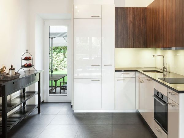 Bucătărie modernă în formă de L, cu dulapuri albe foarte lucioase la un capăt și dulapuri suspendate din furnir de culoare wenge închis