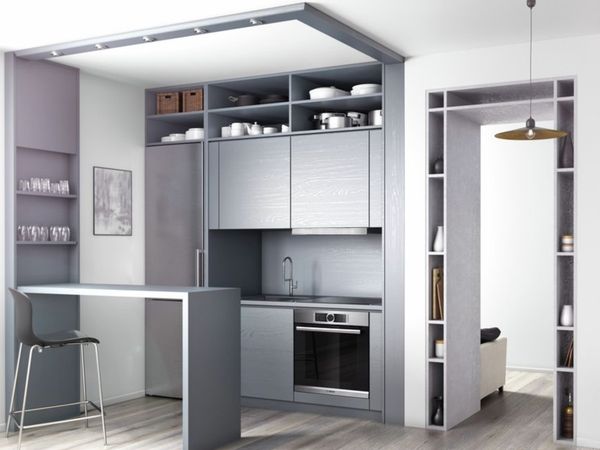 Small, modern black and white one wall kitchen with built-in cooking appliances and white crockery on open shelves.