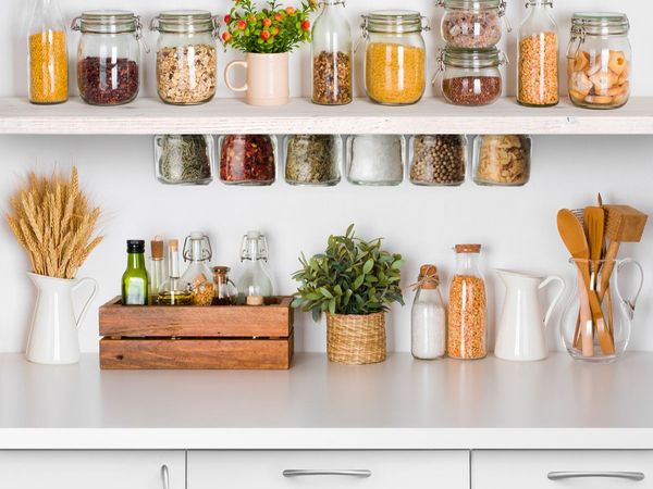 Simple open shelf with glass jars on both sides of the shelf holding a colorful mix of spices, cereals and pasta