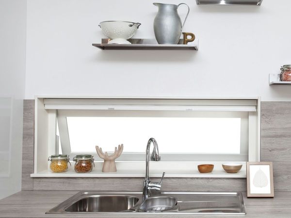 Baltos virtuvės siena su dviem lentynomis virš virtuvės lango ir dekoratyviniais elementais ant palangės
