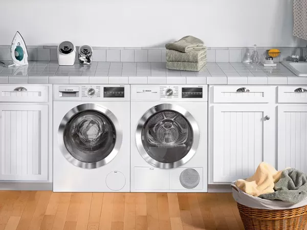 Kompakta veļas mazgājamā mašīna un žāvētājs, kas novietoti viens otram blakus, veļas mazgāšanas telpā