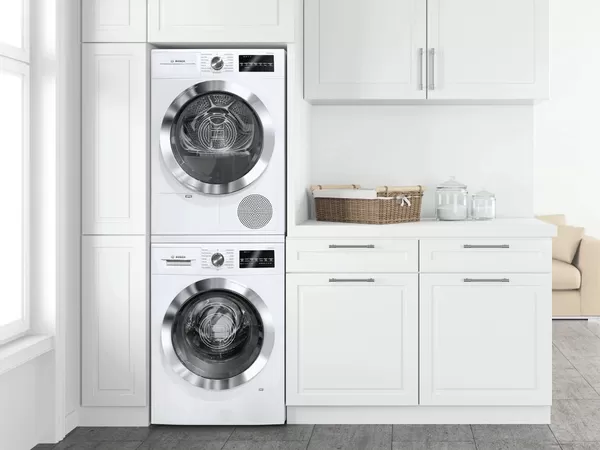 Lavatrice e asciugatrice impilate verticalmente in una cucina di campagna bianca dal taglio moderno