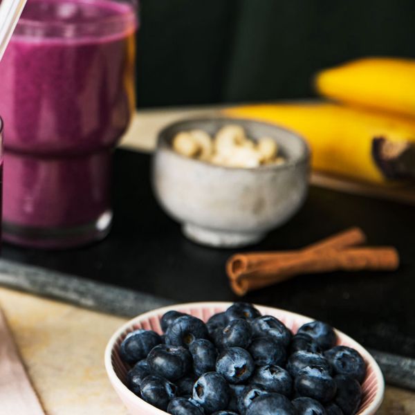 blueberries, cinammon, bananas and cashews on a table with a smoothie